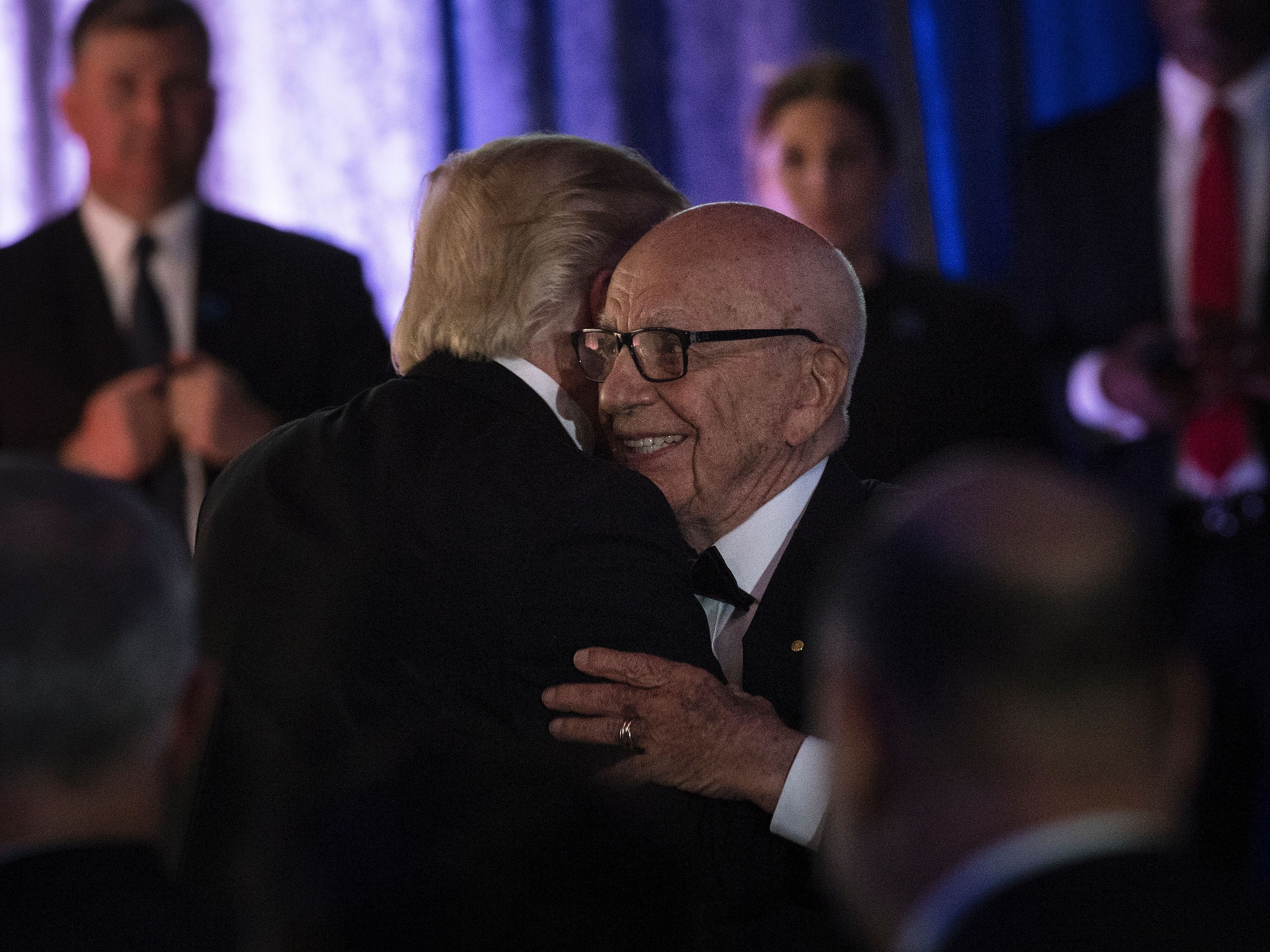 caption: President Trump is embraced by media mogul Rupert Murdoch during a 2017 dinner in New York to commemorate the 75th anniversary of the Battle of the Coral Sea during World War II.