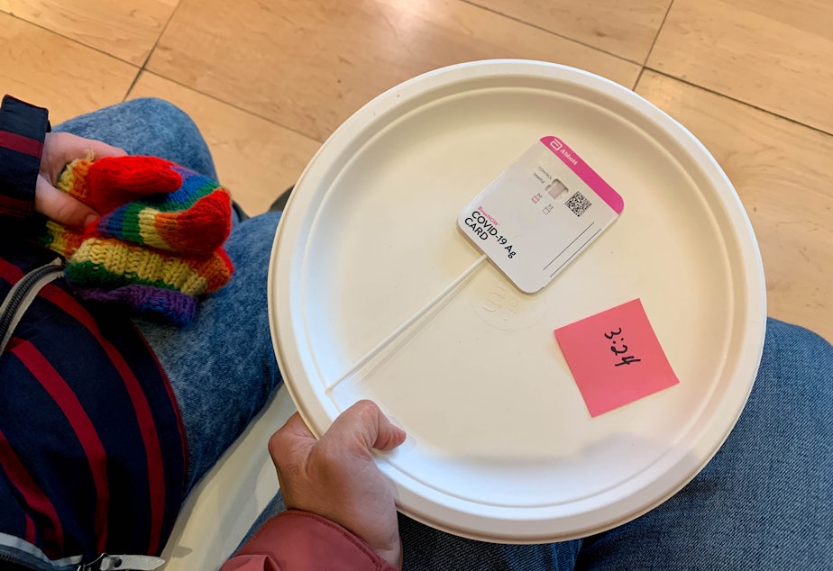 caption: After waiting in line for an antigen test, Seattle Public Schools students put their test on a paper plate and waited 15 minutes. After 15 minutes, they or their parents uploaded the result online using a QR code.