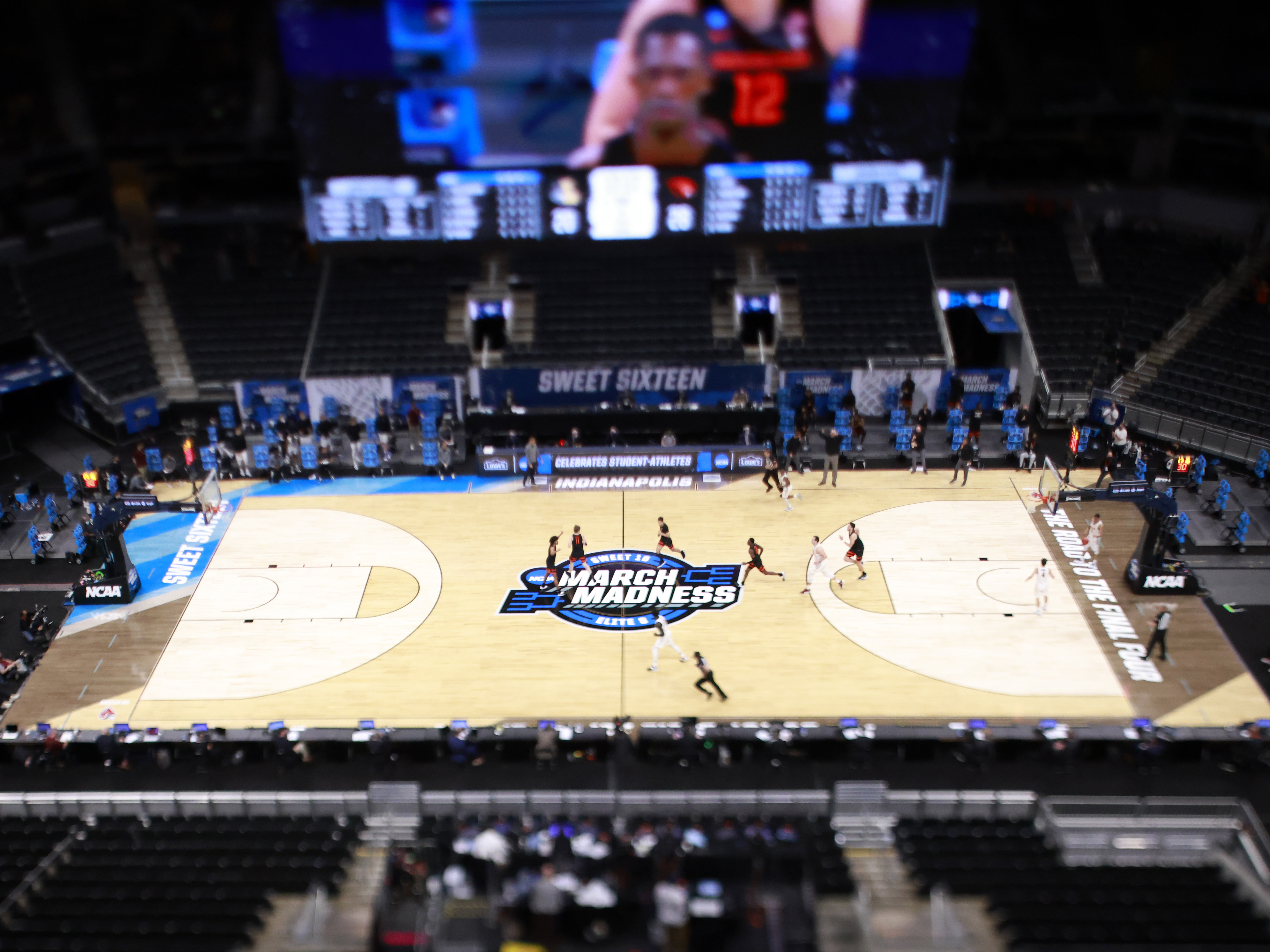caption: The March Madness logo on the court during the Sweet Sixteen round of the 2021 NCAA Men's Basketball Tournament in Indianapolis. Soon, some college athletes can get money when using their name, image or likeness.