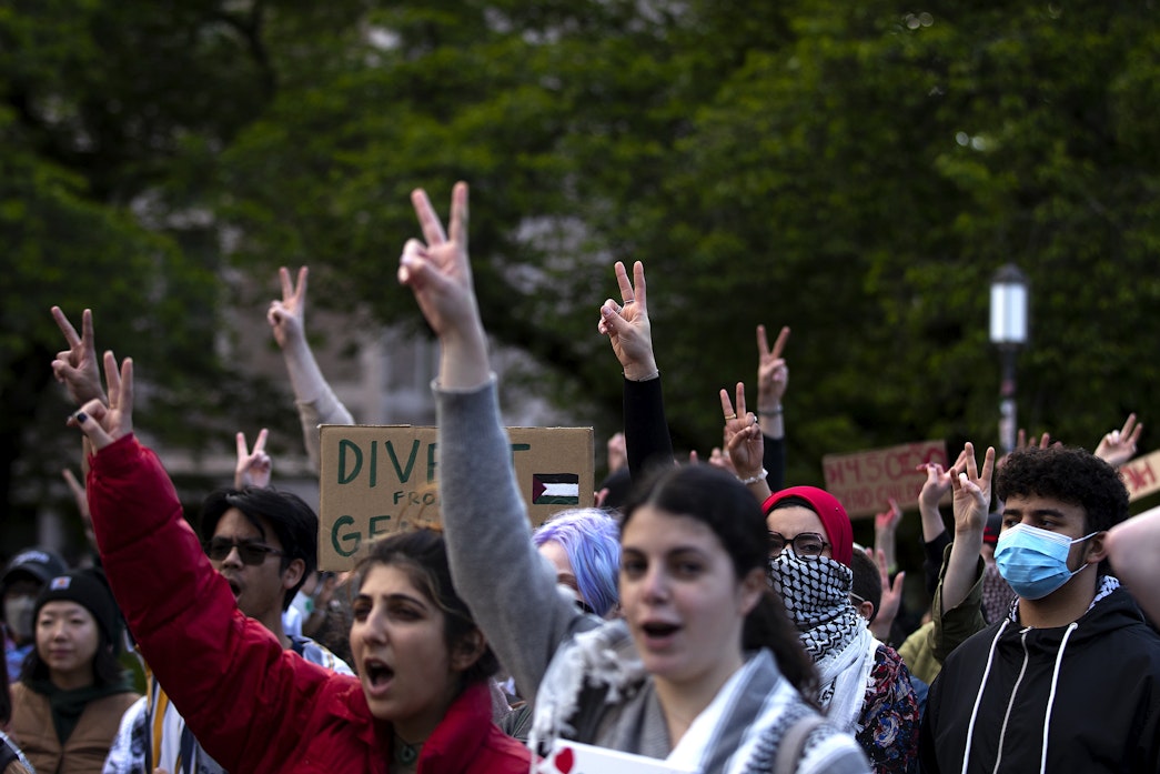 caption: Students and protesters raise peace signs in the air while listening to speakers at the encampment for Palestine on Tuesday, May 7, 2024, at the University of Washington Quad in Seattle. Large crowds amassed ahead of a speech by Turning Point USA founder Charlie Kirk at the HUB on UW's campus. 