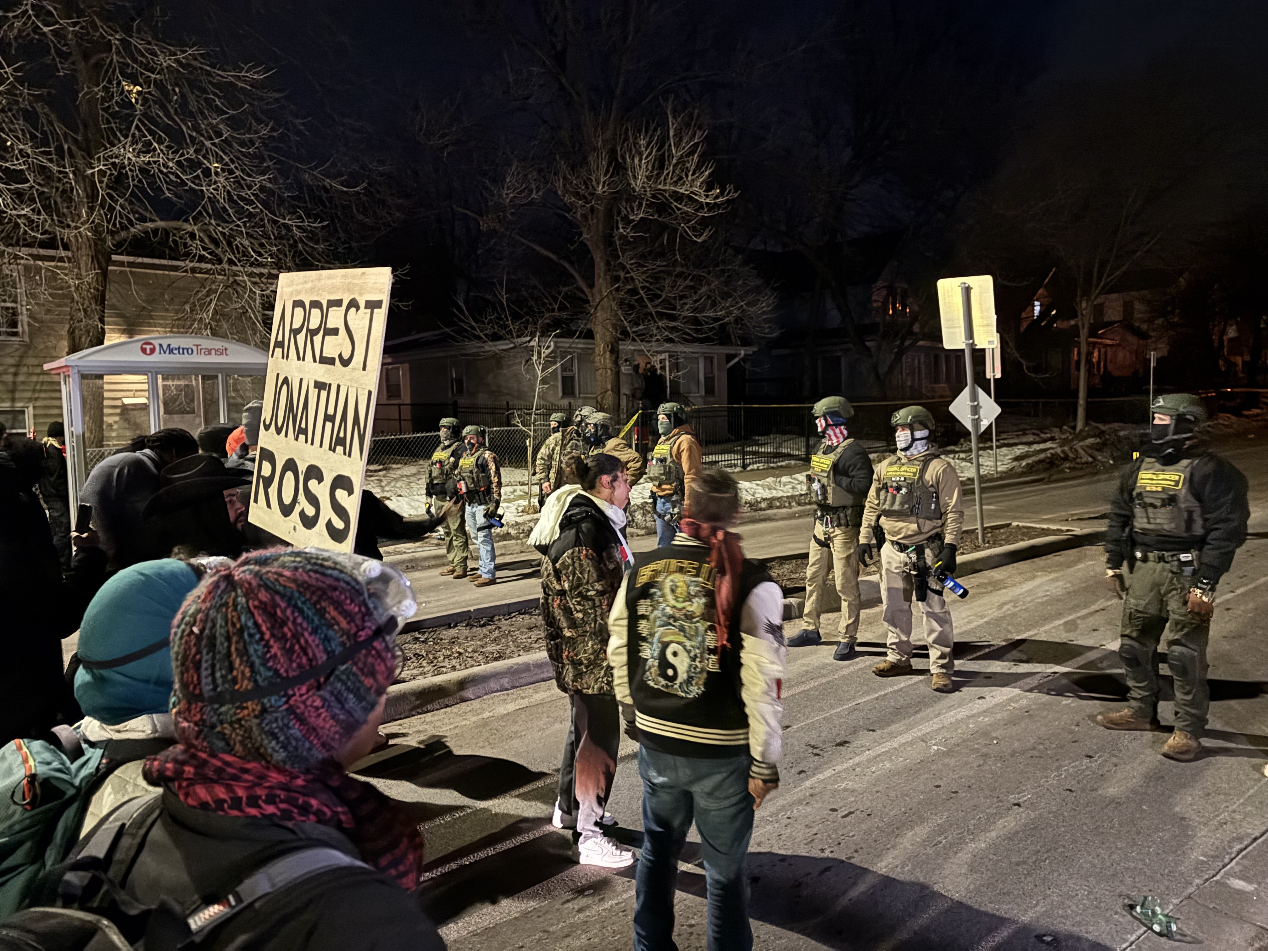 caption: Demonstrators stand in front of federal immigration agents protecting the scene where an Immigration and Customs Enforcement agent shot a Venezuelan immigrant in the leg on January 15, 2026 in Minneapolis.