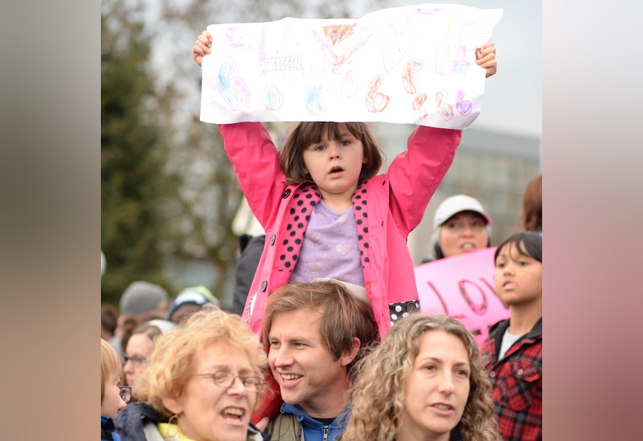 caption: Brian Wahlberg gives daughter Luciena a good view of the proceedings as the crowd sings at Cal Anderson Park in Seattle.