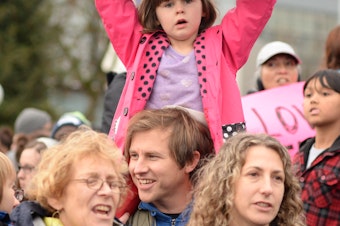 caption: Brian Wahlberg gives daughter Luciena a good view of the proceedings as the crowd sings at Cal Anderson Park in Seattle.