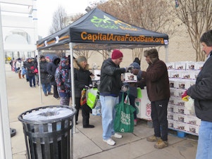 caption: Federal workers wait for food distribution to begin Saturday at a pop-up food bank in Rockville, Md. The Capital Area Food Bank is distributing free food to government employees during the shutdown.