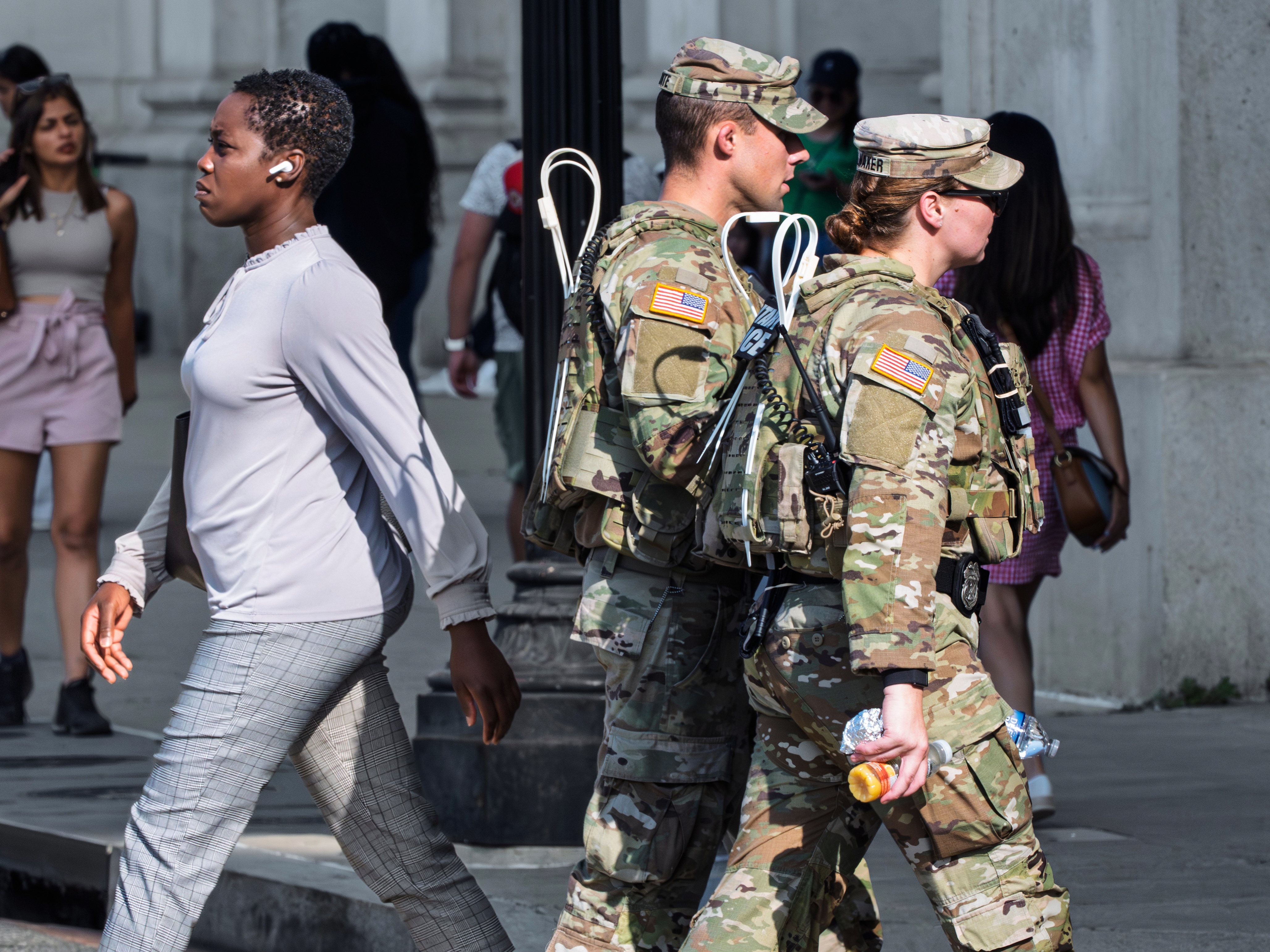 caption: National Guard personnel keep watch as travelers arrive at the entrance to Union Station near the Capitol, in Washington, D.C., on Thursday, Aug. 14, 2025.