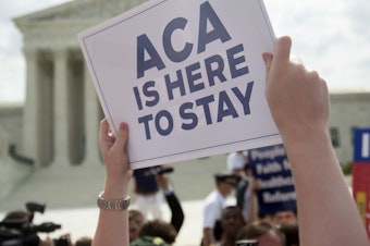 caption: A demonstrator celebrated outside the U.S. Supreme Court in 2015 after the court voted to uphold key tax subsidies that are part of the Affordable Care Act. But federal taxes and other measures designed to pay for the health care the ACA provides have not fared as well.