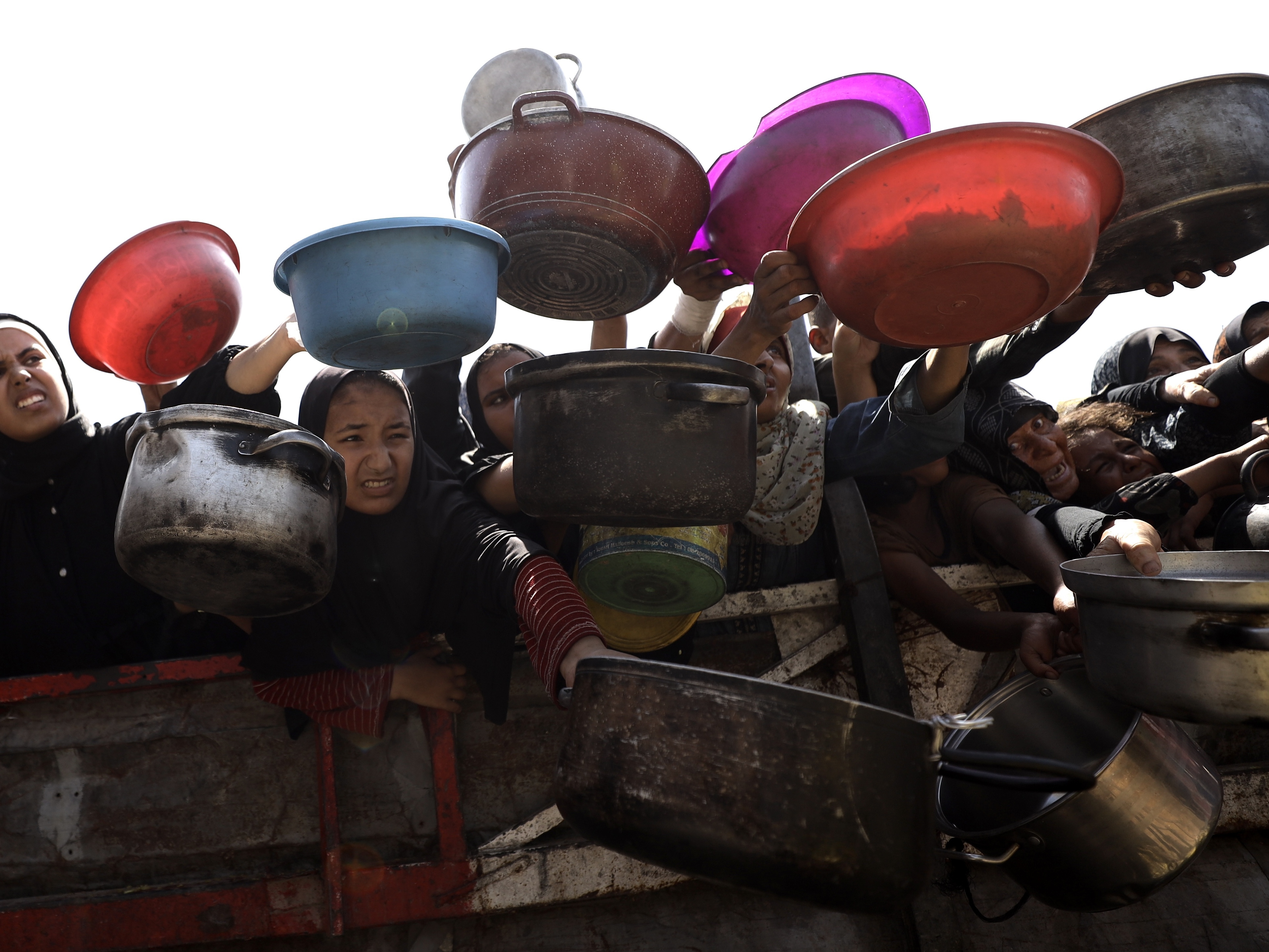 caption: Palestinians, including children, receive hot meals distributed by charity organizations as people struggle to access food due to an Israeli food blockade in Gaza City, Gaza, on Aug. 23.