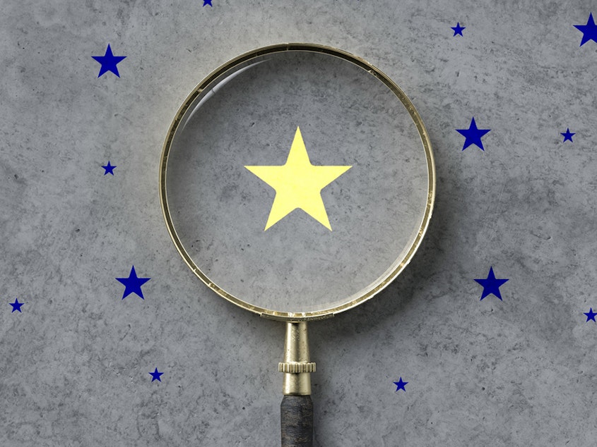 magnifying glass with a yellow star mark as symbol for finding a solution on concrete background - 3d illustration