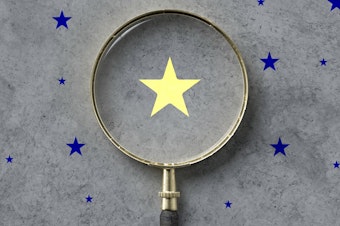 magnifying glass with a yellow star mark as symbol for finding a solution on concrete background - 3d illustration