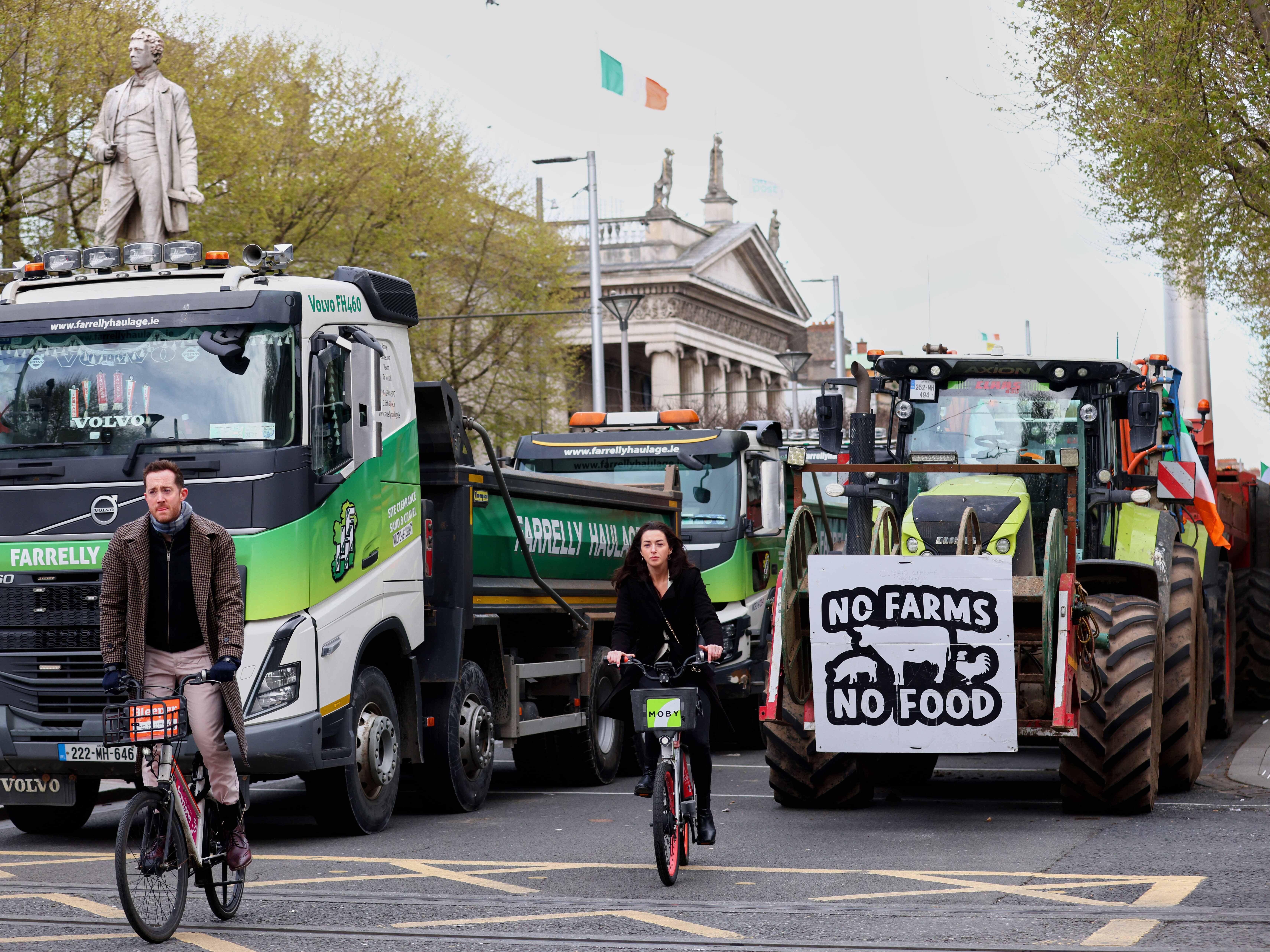 caption: Cyclists ride past tractors blocking O'Connell Street on the fifth day of the National Fuel Protest, in Dublin, Ireland, on Saturday.