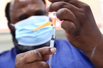 caption: A COVID-19 vaccination dose is prepared at a pharmacy in Baton Rouge, La., on Aug. 17. About 14 million people received their first dose of a COVID vaccine in August.