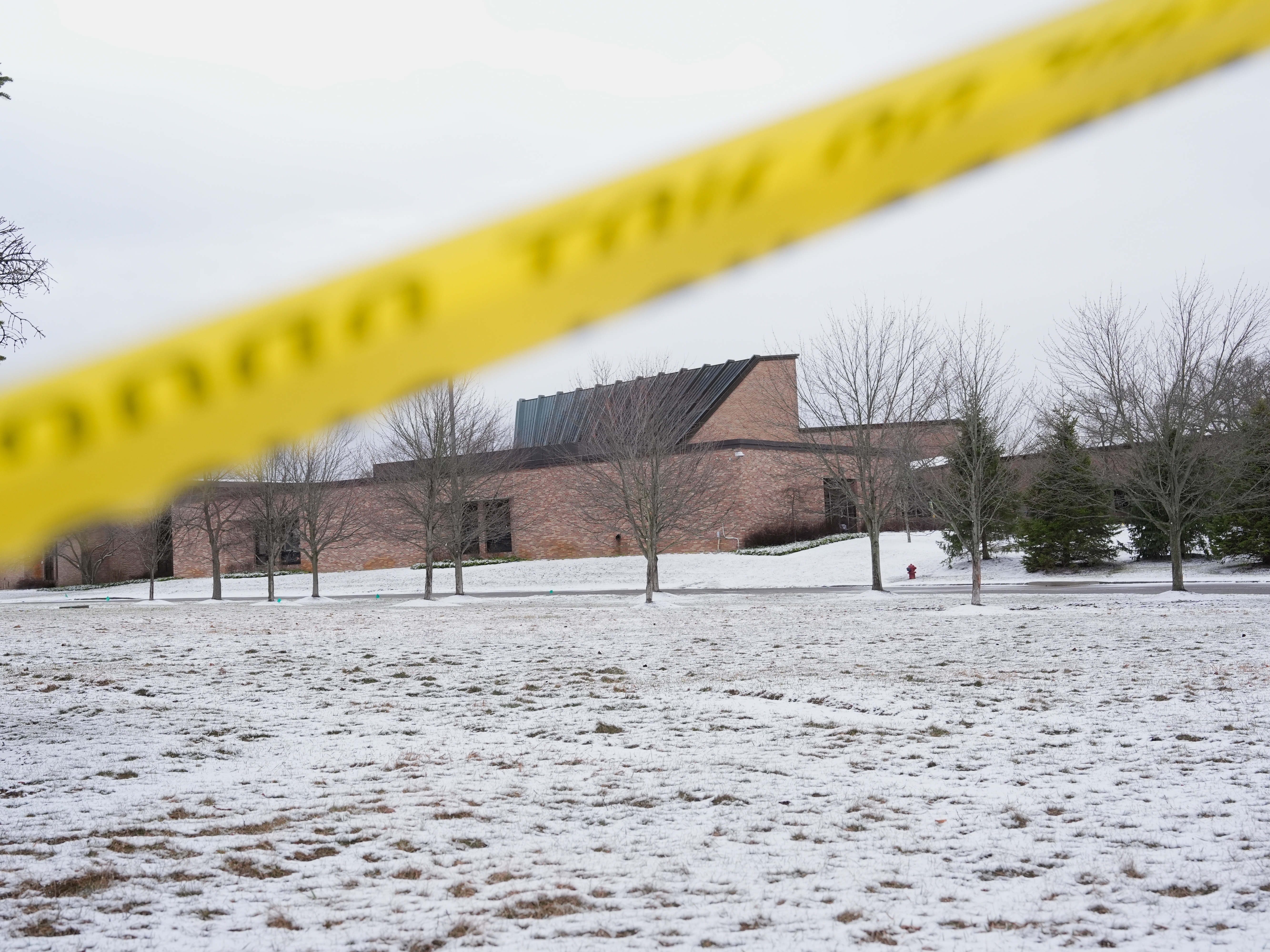 caption: FILE - Police tape hangs outside the Temple Israel synagogue Friday, March 13, 2026, in West Bloomfield Township, Mich.