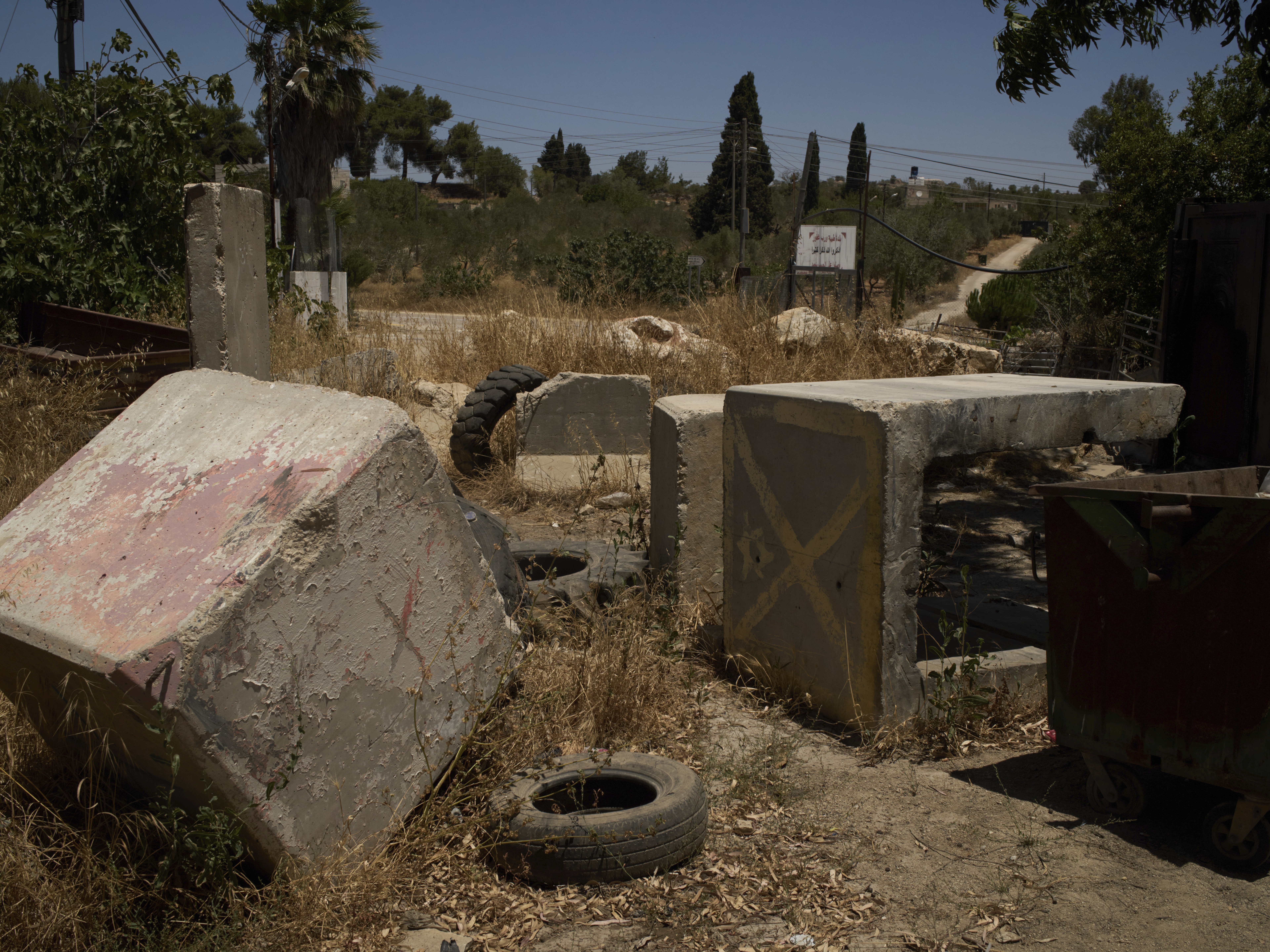 caption: Concrete blocks placed by Israeli soldiers after October 7, 2023, according to local residents, are seen at one of the entrances to the West Bank village of Sinjil, impeding access for Palestinians, on July 9, 2025.
