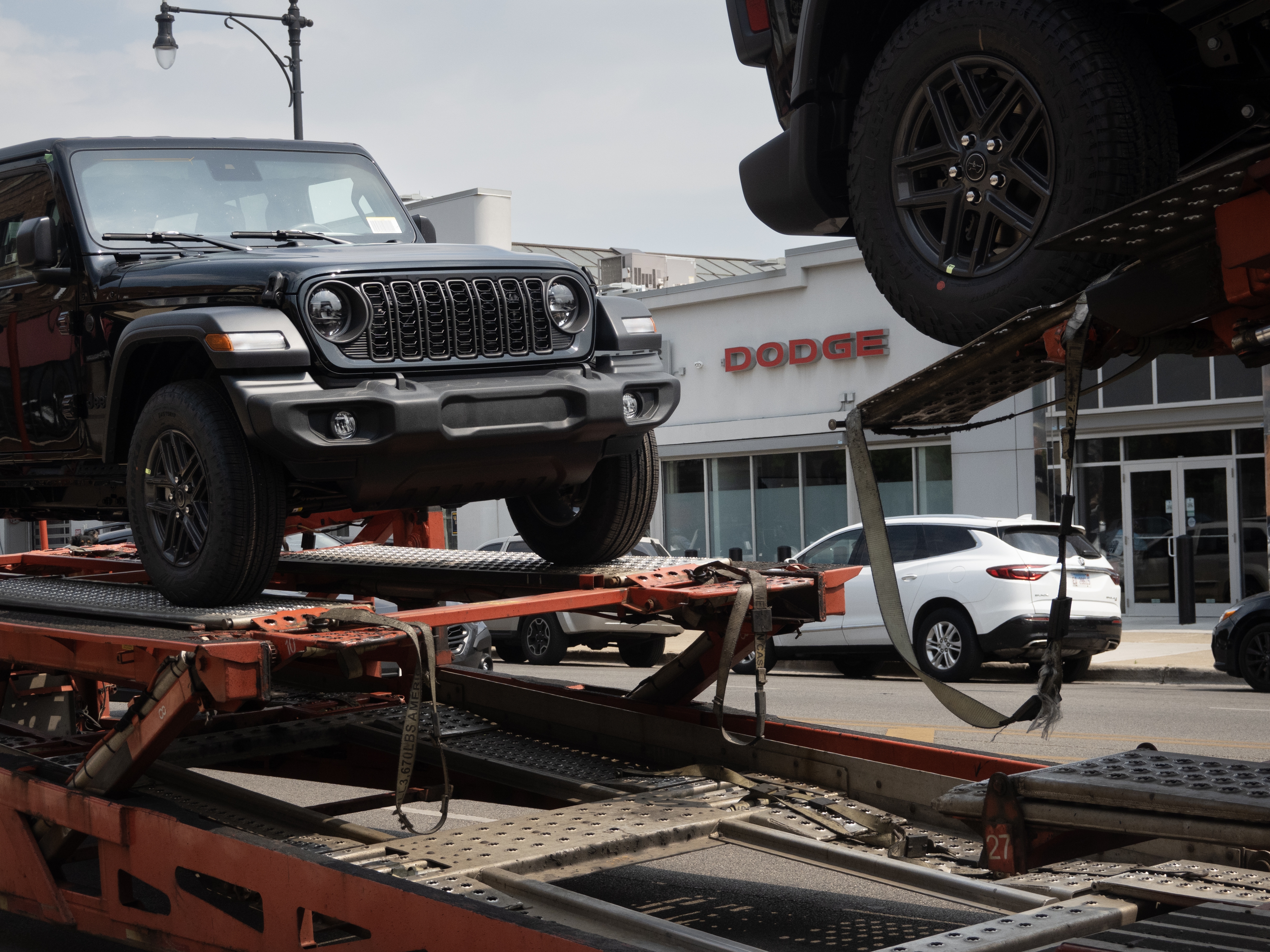 caption: Jeeps are delivered to a dealership in Chicago on June 20, 2024. Stellantis, the parent company of Jeep, reported disappointing earnings for the first half of 2024. 