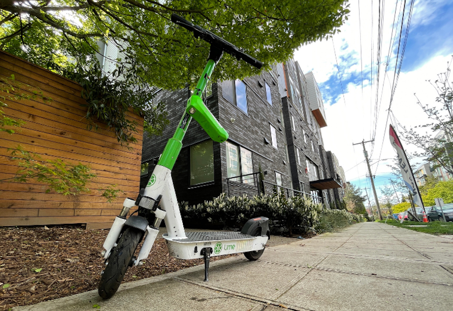caption: A Lime scooter parked on a Northeast Seattle sidewalk. 