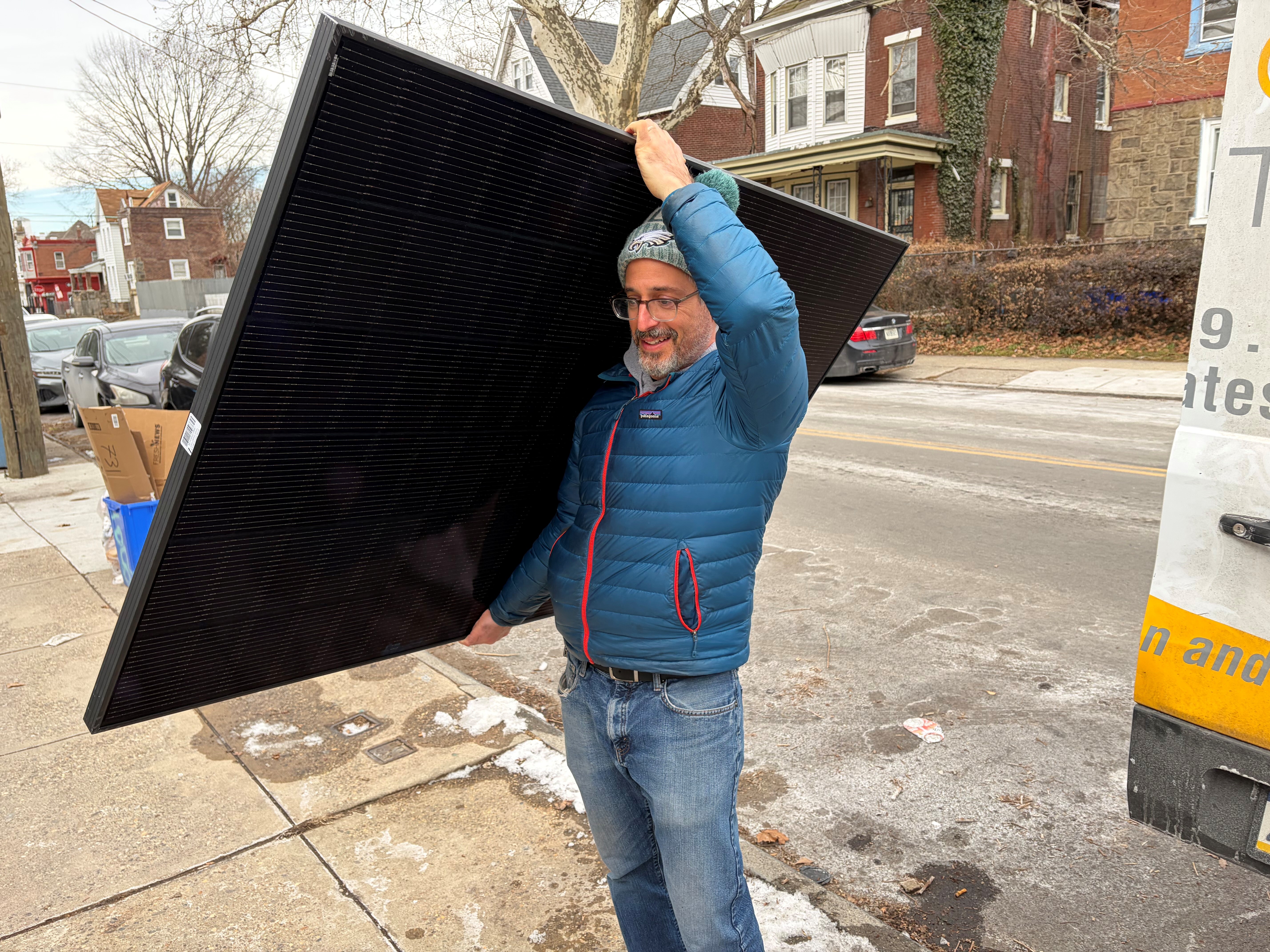 caption: Solar States owner Micah Gold-Markel carries a solar panel from a truck to the house where it will be installed.