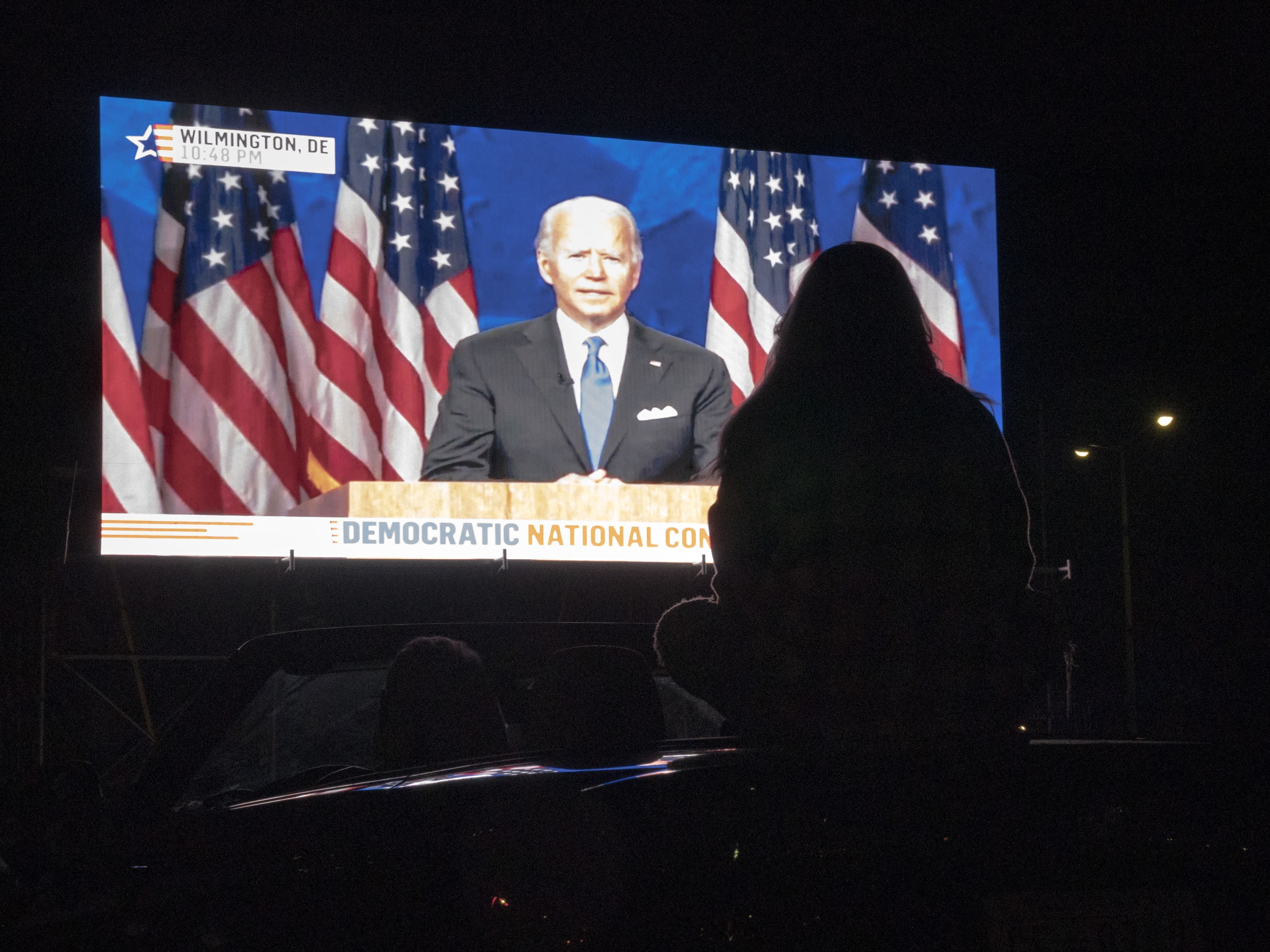 caption: Members of the District of Columbia Democratic Party attend a drive-in watch party in the parking lot of the Robert F. Kennedy Memorial Stadium to watch Democratic presidential nominee Joe Biden accept the Democratic nomination for president on the final night of the Democratic National Convention on August 20, 2020.