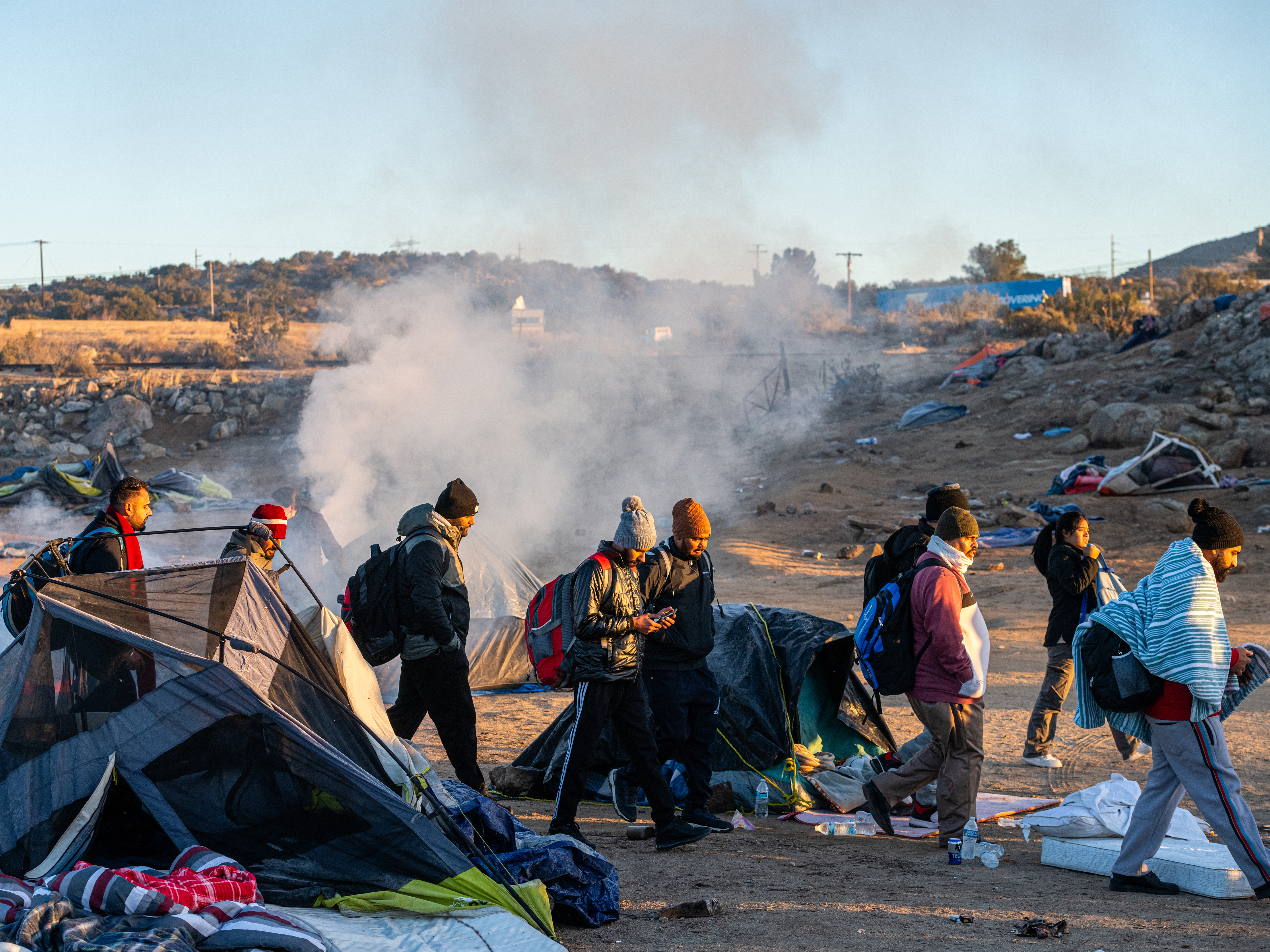 caption: Migrants walk towards a Border Patrol agent in the town of Jacumba. Those crossing the border are often being instructed by cartels to turn themselves over to agents, in order to receive asylum.