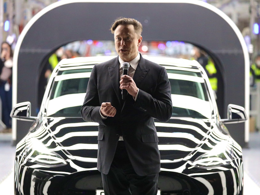 caption: Tesla CEO Elon Musk speaks during the official opening of the new Tesla electric car manufacturing plant on March 22, 2022 near Gruenheide, Germany.