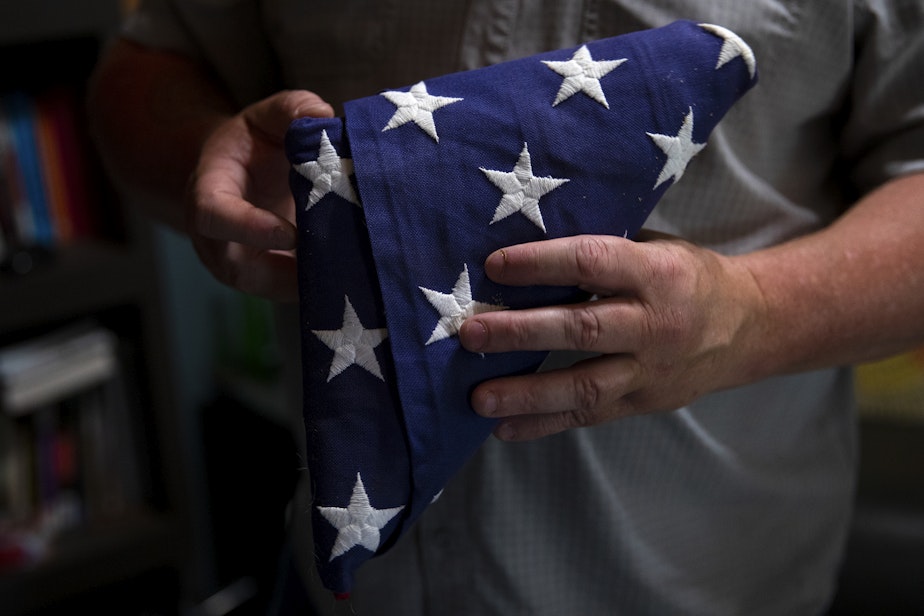caption: Robert Bates, a veteran and counselor who works primarily with other veterans, holds the American flag that he received upon retirement, on Wednesday, July 9, 2025, at his home office in Quincy.