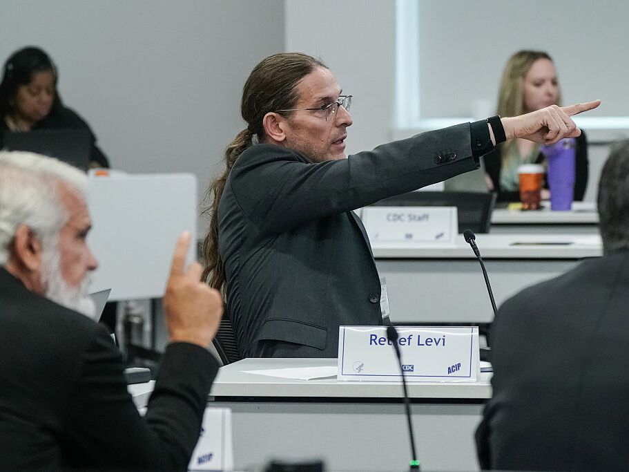 caption: ACIP member Retsef Levi points to a slide while speaking during a meeting of the CDC's Advisory Committee on Immunization Practices on September 18, 2025 in Atlanta, Georgia. The federal vaccine advisory group, recently appointed by Health Secretary Robert F. Kennedy Jr., made recommendations Friday on the COVID vaccine.