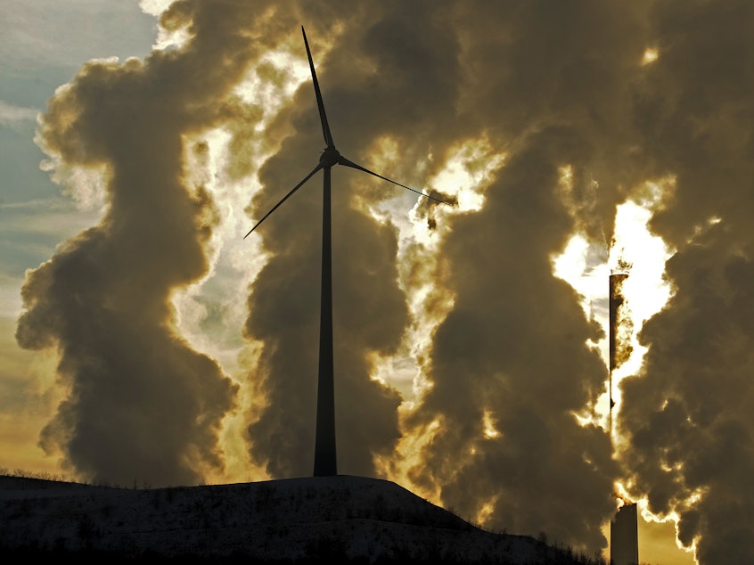 caption: A wind turbine in front of a steaming coal power plant in Gelsenkirchen, Germany in 2010. New reports find countries' latest promises to cut climate emissions are still not enough to avoid the worst impacts from warming.