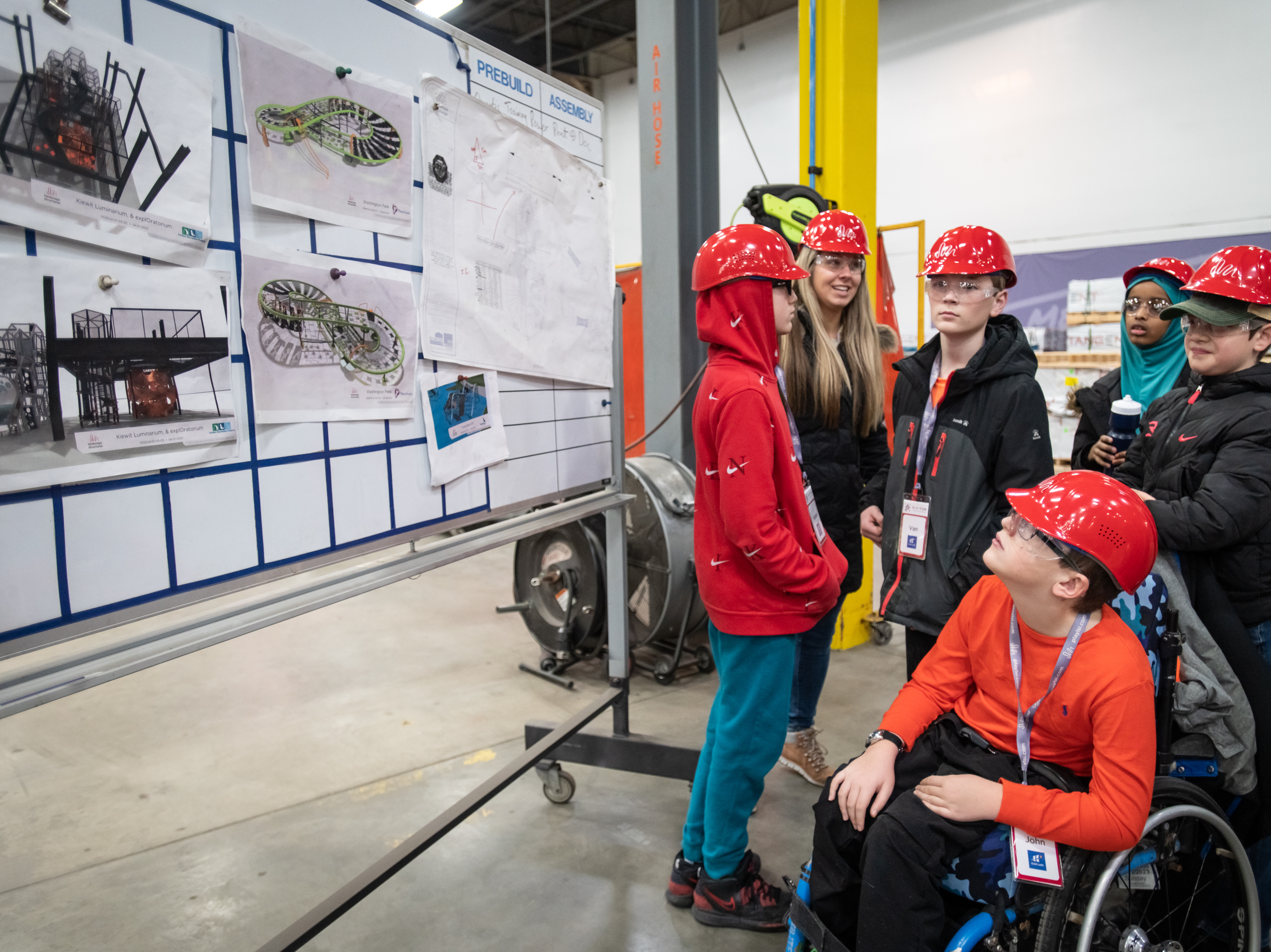 caption: John Buettner (front), a 5th grader at Glen Lake Elementary School in Hopkins, Minn., looks at drawings of playground designs while on a tour at Landscape Structures with his classmates in Delano, Minn.