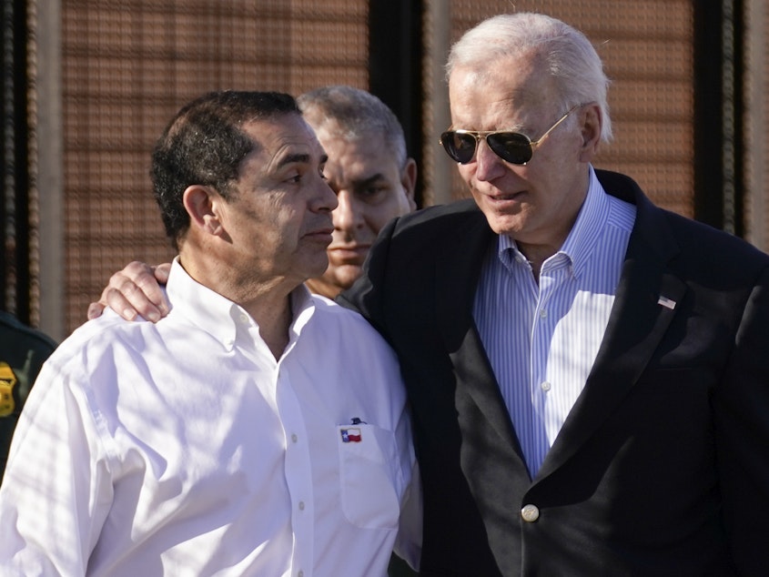 caption: President Joe Biden talks with Rep. Henry Cuellar, D-Texas, left, as they walk along a stretch of the U.S.-Mexico border in El Paso Texas, last month.