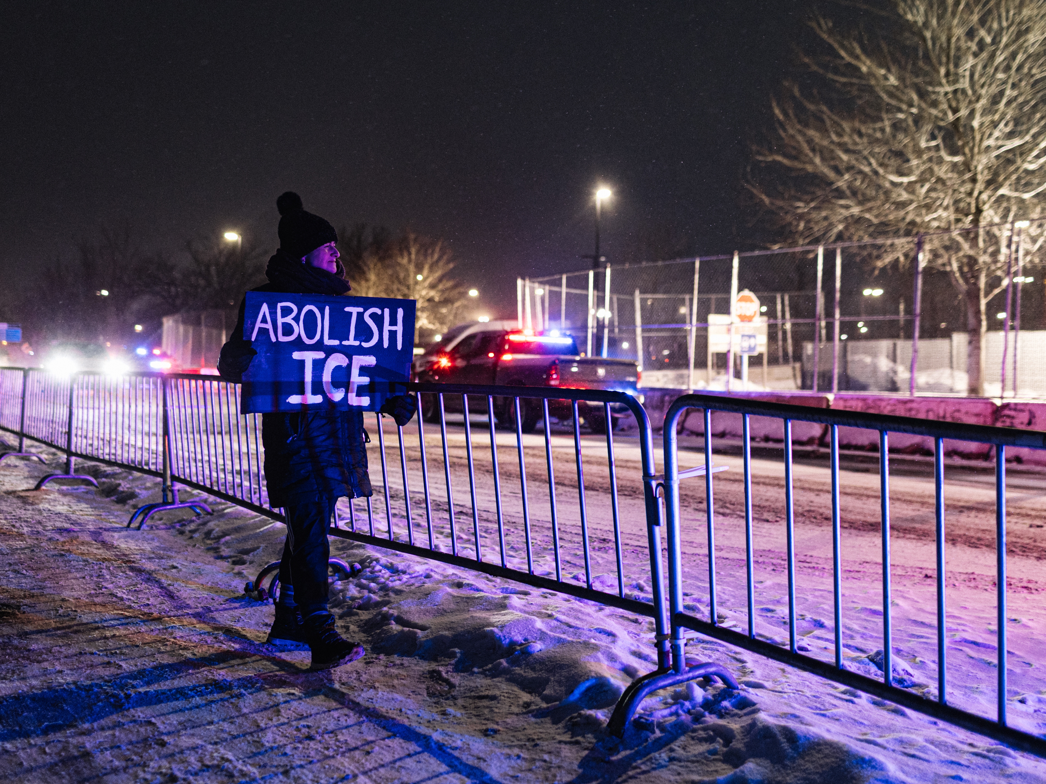 caption: A protester with an anti-ICE sign, stands outside of the Henry Bishop Whipple Federal building on Jan. 18 in Minneapolis, Minn.