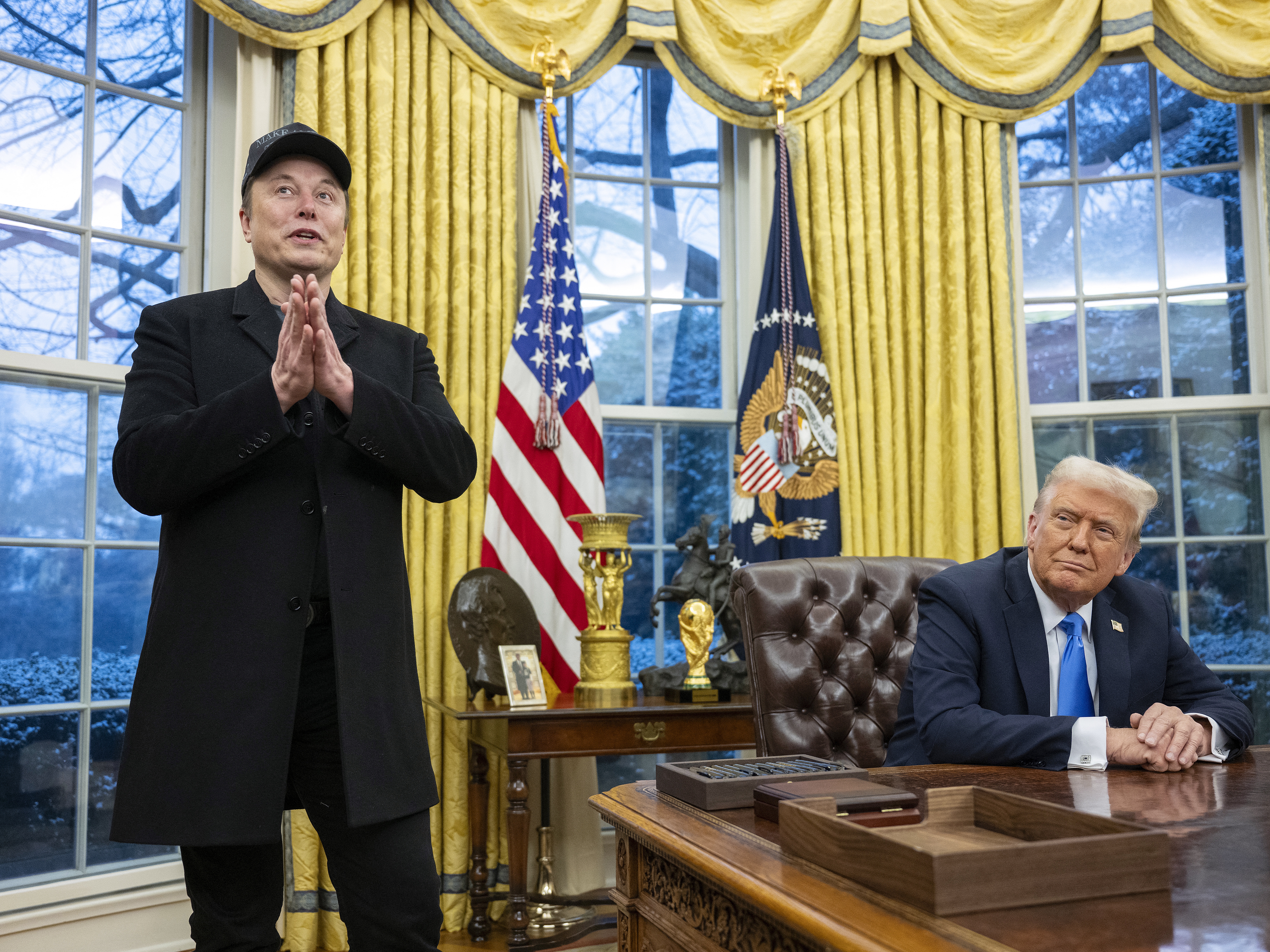 caption: Elon Musk takes questions from reporters as President Trump looks on in the Oval Office of the White House on Tuesday.