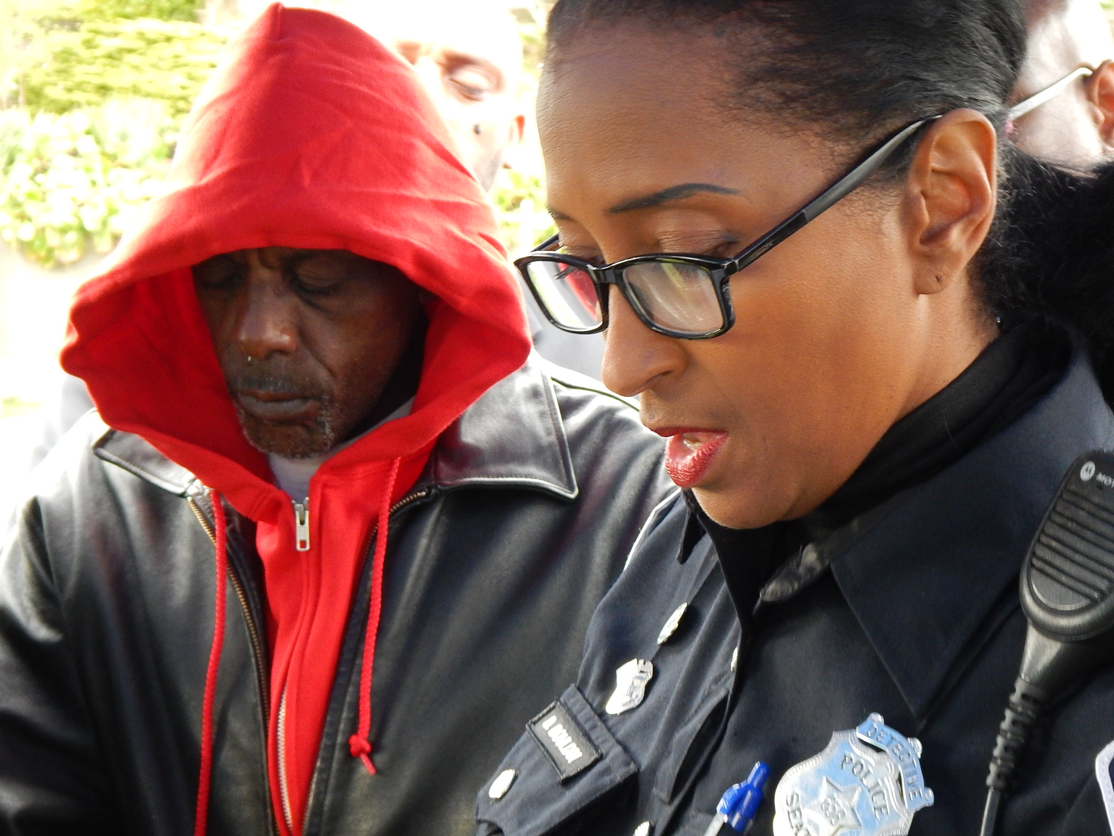 caption: Robert Robinson listens as Seattle Police Detective D. "Cookie" Bouldin reads a poem at a memorial for his son, Robert Jr.