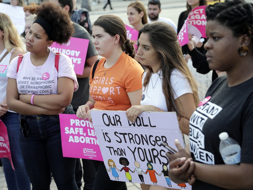 caption: Demonstrators listen to speeches during a rally in support of abortion rights on Thursday in Miami.