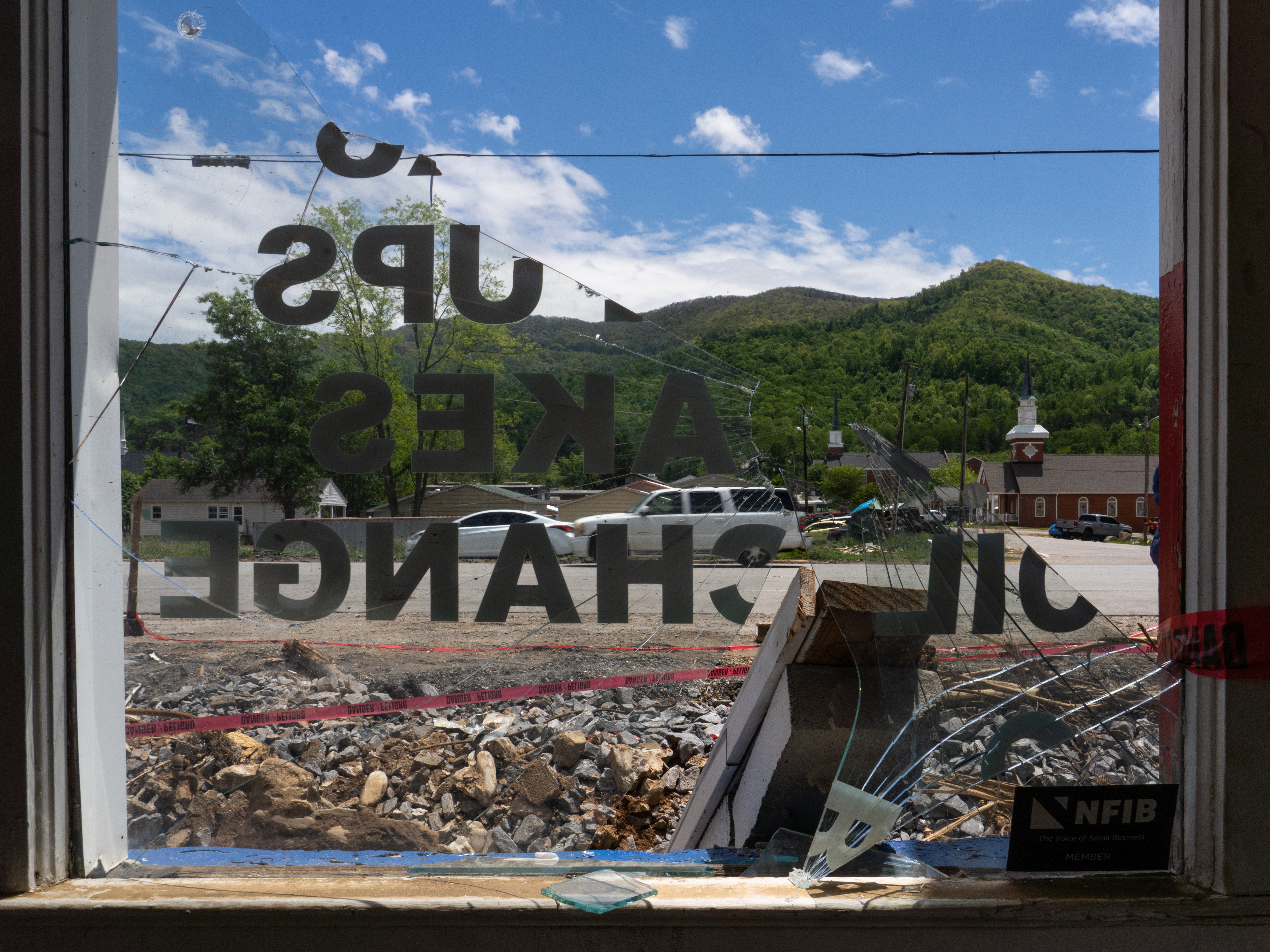 caption: A view of Swannanoa, in western North Carolina, through the broken window of Harper's Automotive on U.S. Highway 70. The shop was heavily damaged by the storm last September.