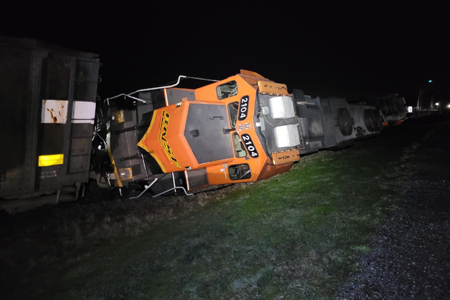 caption: A BNSF locomotive lies on its side after derailing on the Swinomish Reservation, in Anacortes, Washington, March 16, 2023. 