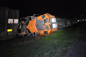 caption: A BNSF locomotive sits on its side after derailing on the Swinomish Reservation, in Anacortes, Washington, March 16, 2023. 