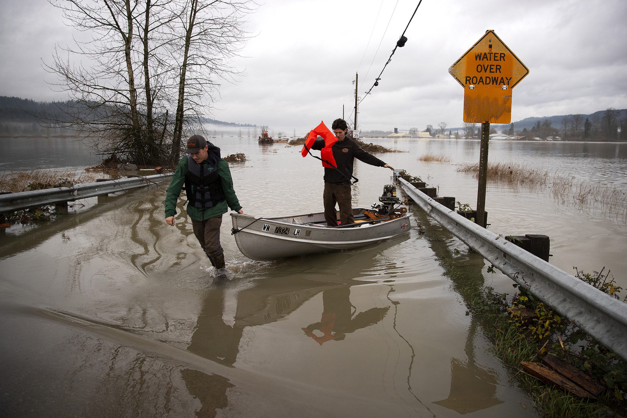 caption: Liam P., left, and Finn Barclay, right, pull their boat out of the water after attempting to visit a friend who’s home is flooded on Friday, December 12, 2025, on West Snoqualmie River Road Northeast in Duvall. Their motor stopped working and they weren’t able to make it to their friend’s home. 