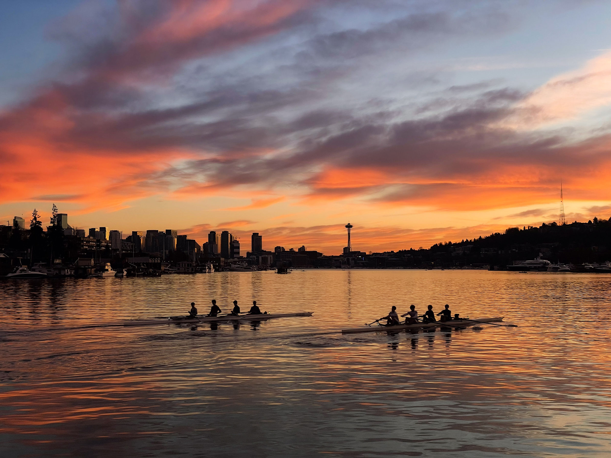 caption: The sun sets on Lake Union as rowers make their way across the water, in Seattle. 