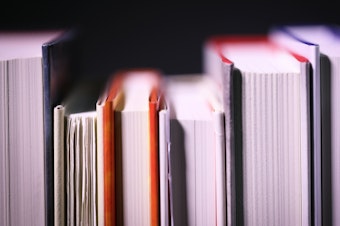 A close-up of a shelf of books, shown from the side of the pages.