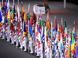 caption: The flags of the participating nations are displayed in the parade of athletes during the opening ceremony of the Tokyo 2020 Paralympic Games on Tuesday.