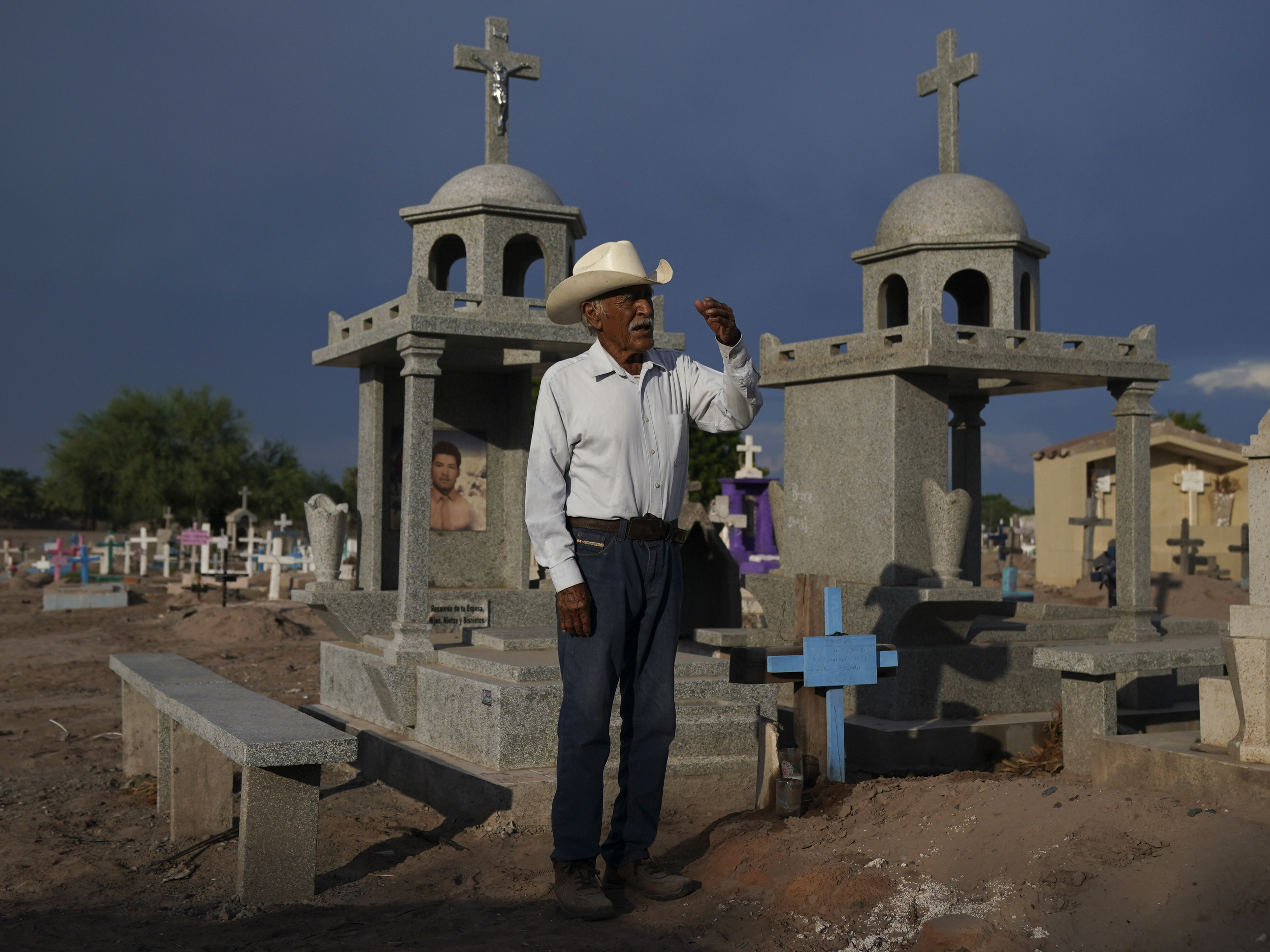 caption: Guillermo Rojo, the father of slain water-defense leader Tomás, prays next to his tomb, decorated with a blue cross, at the cemetery in Potam, Mexico, Tuesday, Sept. 27, 2022.