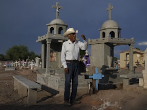 caption: Guillermo Rojo, the father of slain water-defense leader Tomás, prays next to his tomb, decorated with a blue cross, at the cemetery in Potam, Mexico, Tuesday, Sept. 27, 2022.