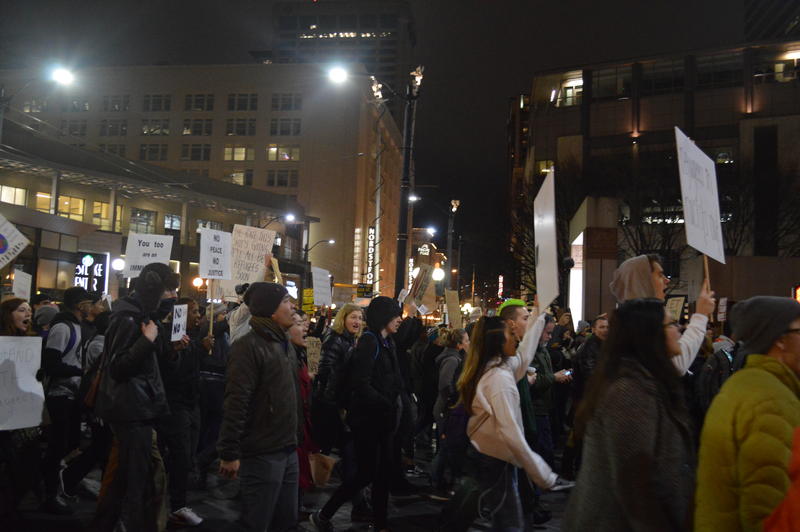 caption: Protesters march through downtown Seattle after a rally for immigrant rights at Westlake Park

