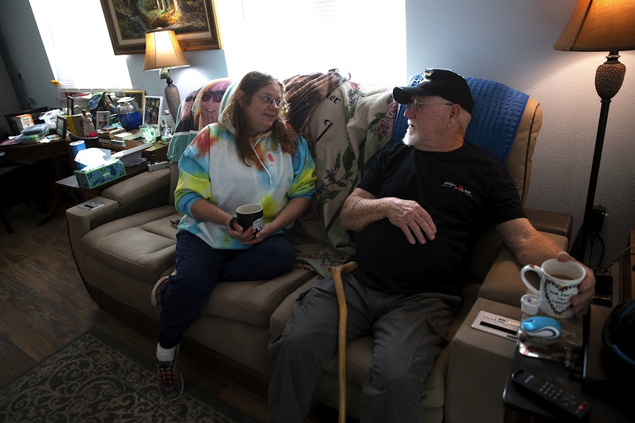 caption: Rita Cooper has been caring for her father, Allan Opie, for the last 3 years. Here, they talk on the couch together on Thursday, October 19, 2023, at their home in Cashmere.