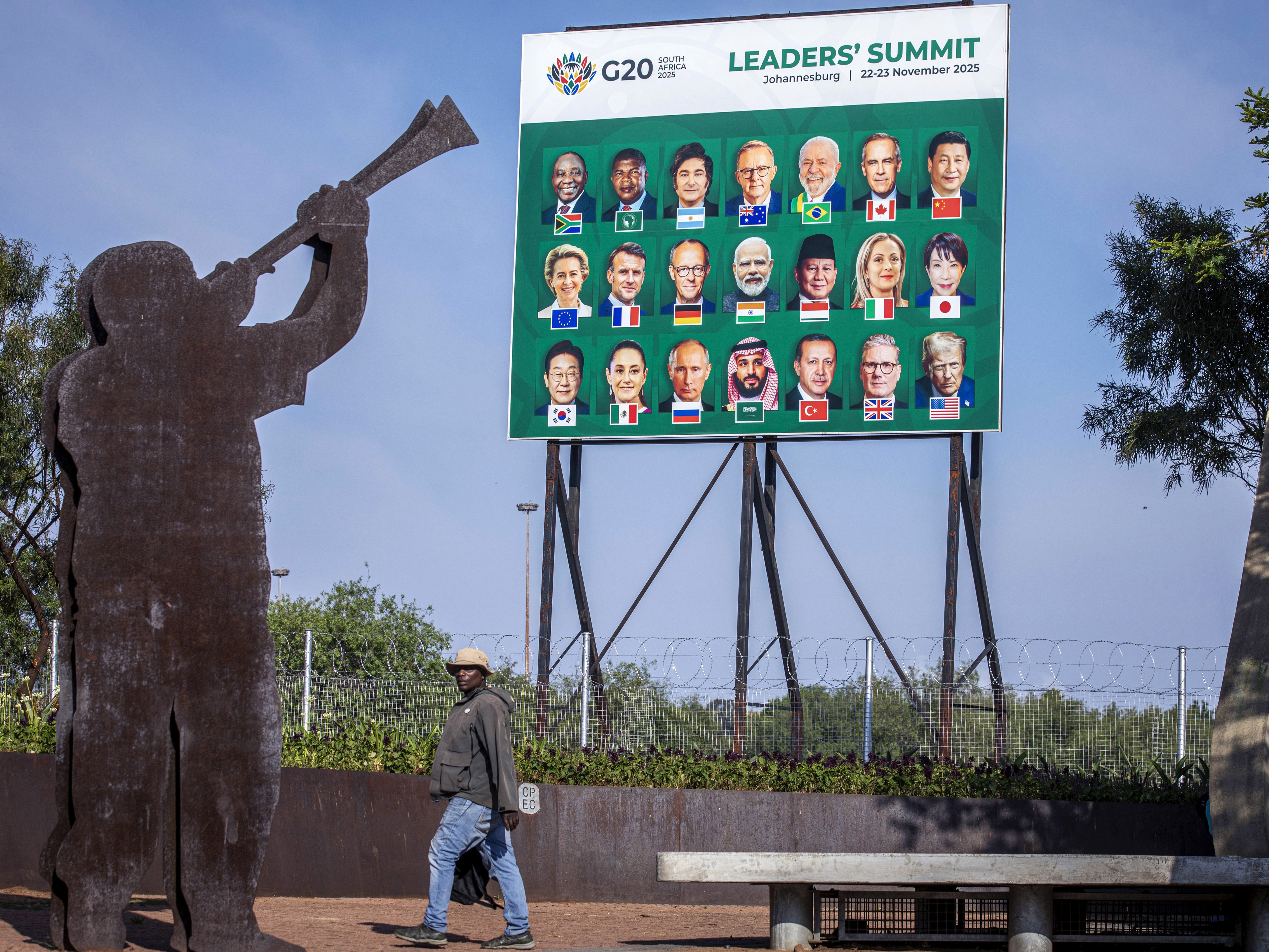 caption: A man walks past a billboard with portraits of G20 leaders at the entrance for the Nov. 22nd G20 Leaders's Summit . The meeting of the Group of twenty heads of state will convene in Johannesburg, but the U.S. will not be attending.