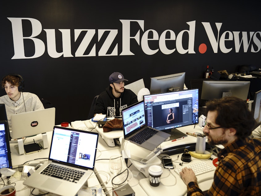 caption: Members of the BuzzFeed News team work at their desks at BuzzFeed headquarters, December 11, 2018 in New York City.
