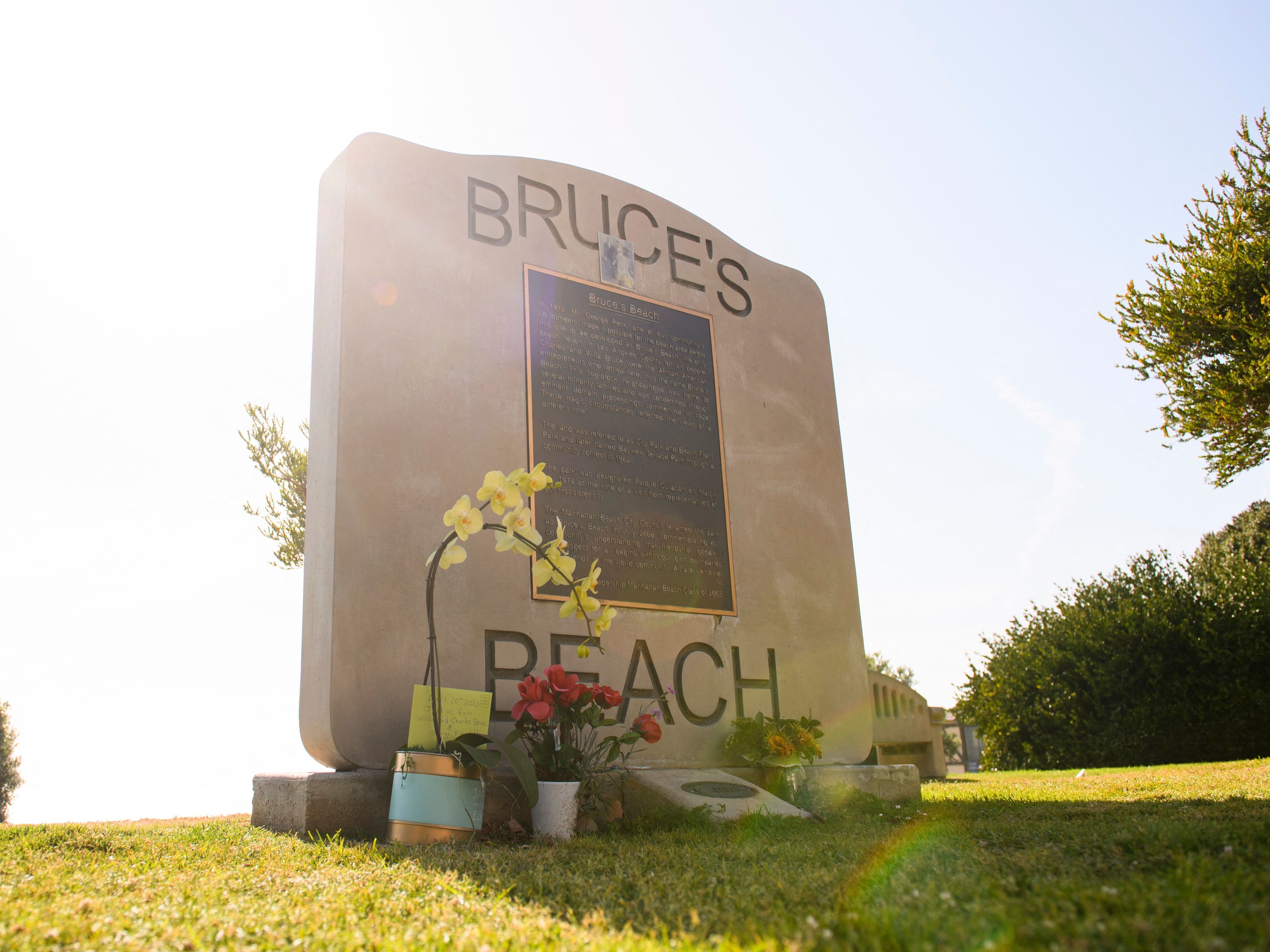 caption: Flowers in support of the Bruce Family and George Floyd stand at Bruce's Beach in April in Manhattan Beach, California.