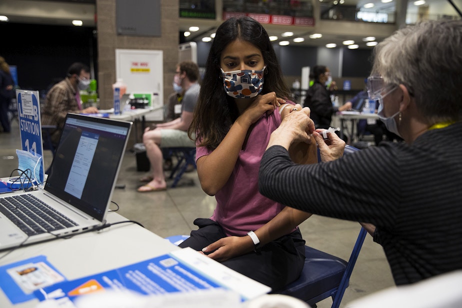 caption: Volunteer Janet Welle administers a Covid-19 vaccine for Shreya Magesh, 23, on Thursday, April 15, 2021, at Lumen Field Event Center in Seattle. As of Thursday, anyone 16 years of age and older is eligible.
