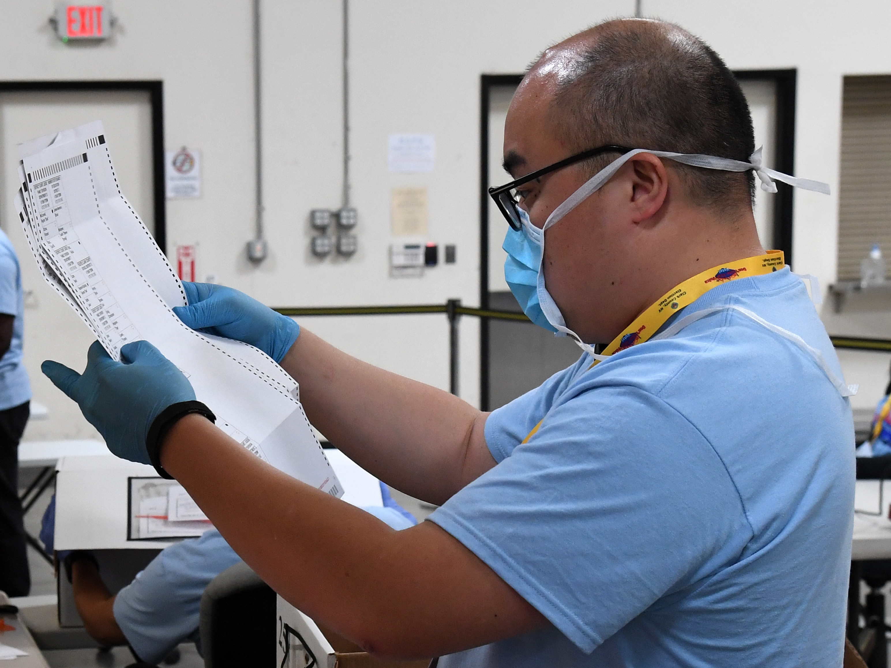 caption: Clark County, Nev., election worker Stean Durias scans mail ballots at the Clark County Election Department earlier this month.