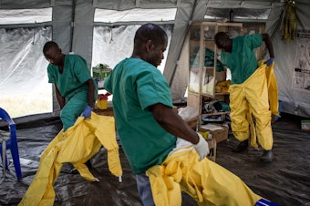 caption: A team of medical workers don protective equipment before entering an Ebola Treatment Center in Beni, the epicenter of the outbreak in the Democratic Republic of the Congo.