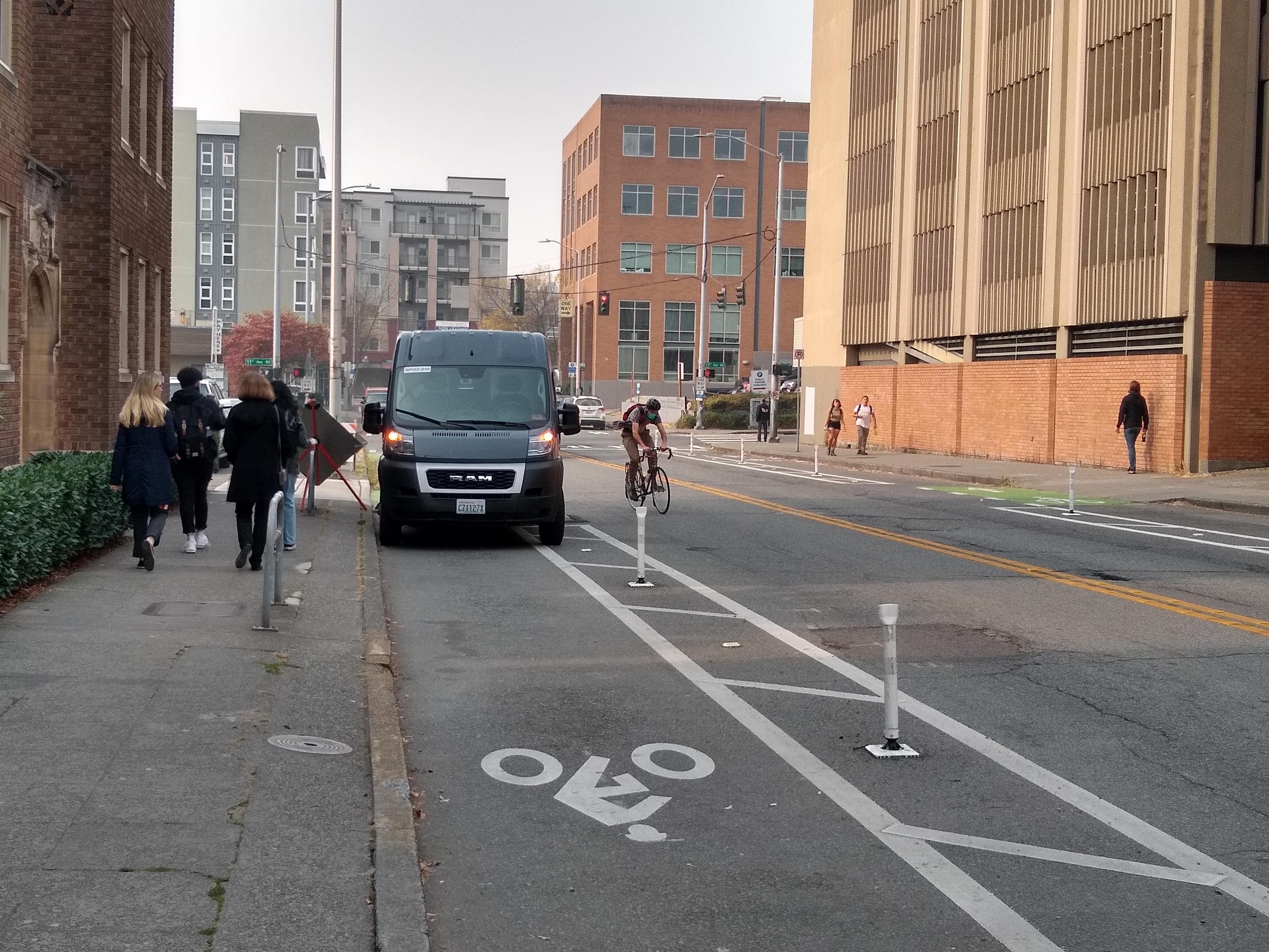 caption: A bike commuter exits a protected bike lane to get around an Amazon delivery truck in Seattle's University District on Oct. 19, 2022.